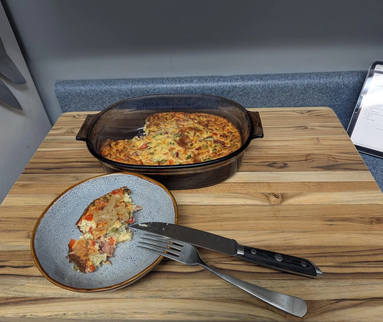 A slice of savory bacon pie on a plate beside the baking dish