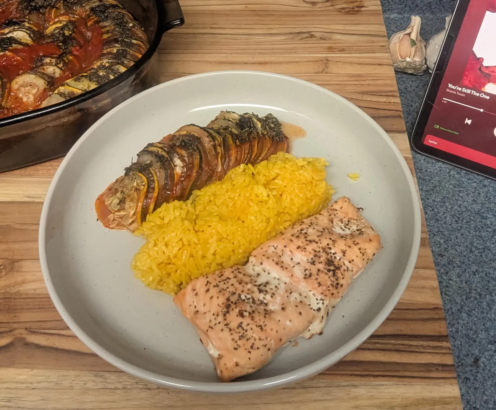 A spiral of sliced ratatouille vegetables next to turmeric rice and salmon