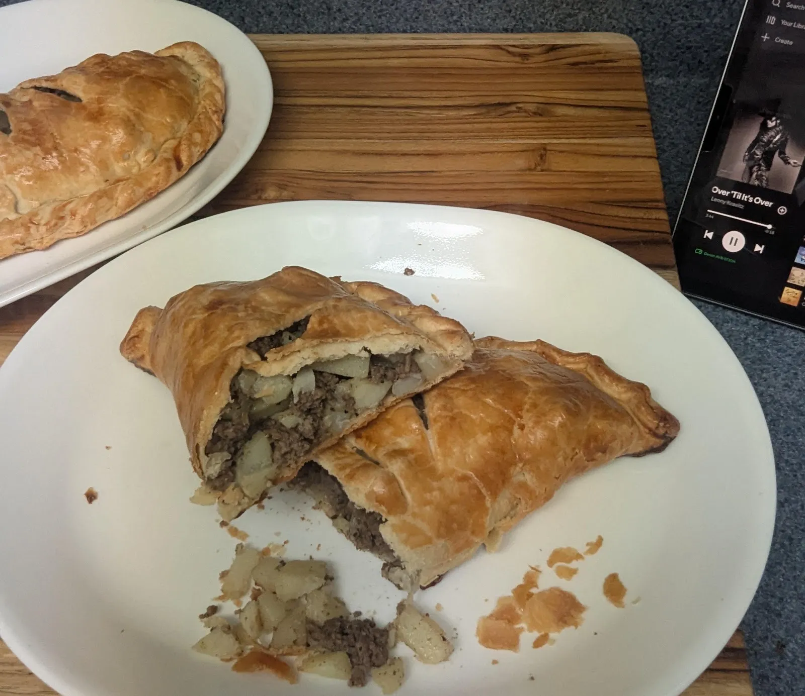 Two golden Cornish pasties, one cut open to show the beef filling