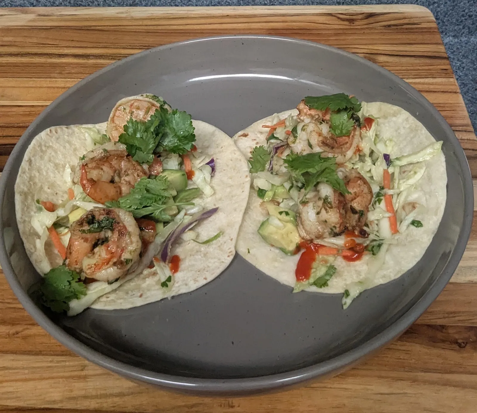Shrimp tacos with slaw and sriracha on a grey plate